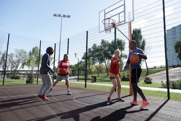 Молодой коллектив. Симпатичные молодые люди играют вместе во время тренировки по баскетболу