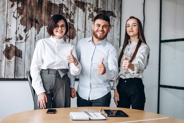 Young team of three showing showing thumb up