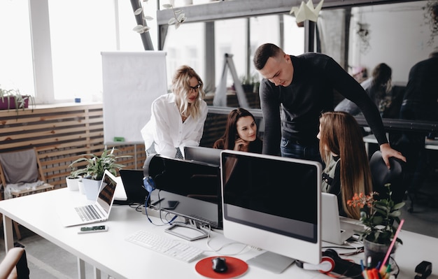 Young team works at a desks with a computer and laptops in a light modern open space office