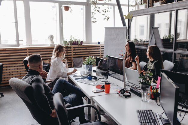 Photo young team works in a spacious light modern open space office sitting at a desks with a computer and laptops