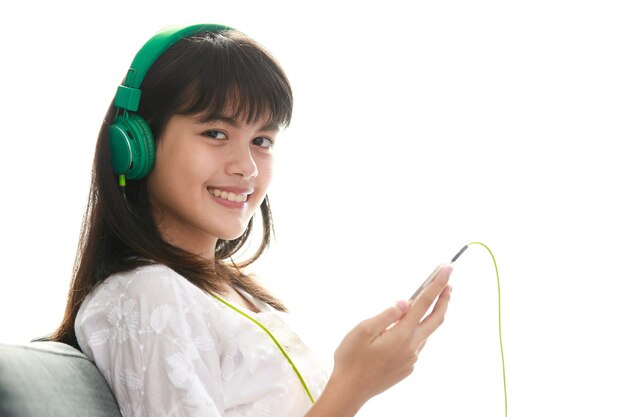 행복한 방식으로 집에서 헤드폰과 smarthphone으로 음악을 듣고 젊은 10대 아시아 소녀