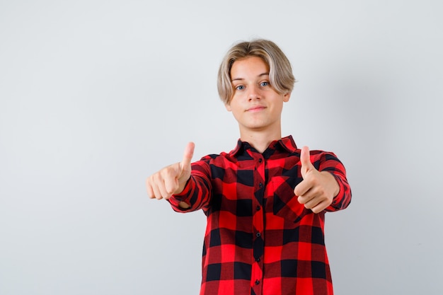 Young teen boy in checked shirt showing double thumbs up and looking confident , front view.