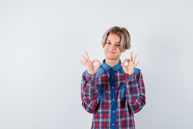 Photo young teen boy in checked shirt showing ok sign and looking happy , front view.