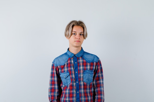 Young teen boy looking at camera in checked shirt and looking sensible. front view.