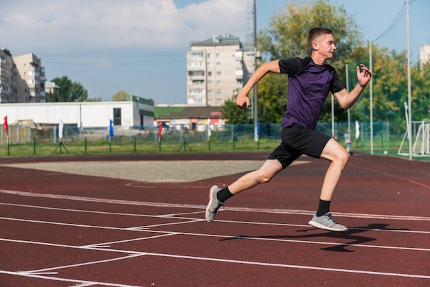 屋外のスタジアムのランニング トラックで走っている若い十代の少年