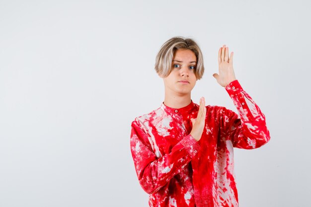 Young teen boy in shirt trying to block himself with hands and looking frightened , front view.