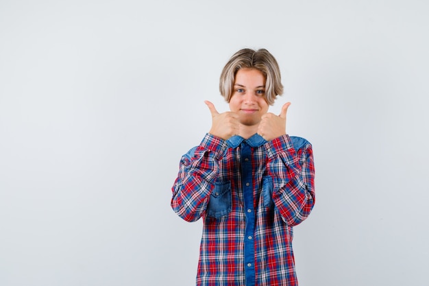 Young teen boy showing double thumbs up in checked shirt and looking merry