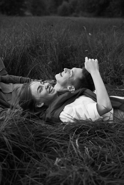 young teen couple laugh on a grass on a field in september