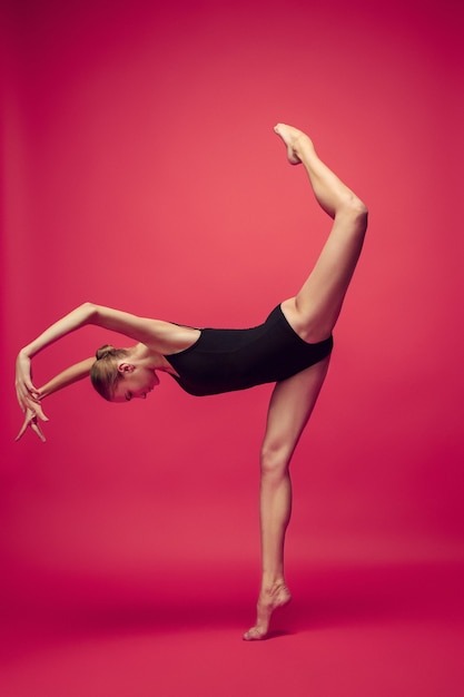 Фото Молодой подросток танцор танцует на красном фоне студии. проект балерины с кавказской моделью. концепция балета, танца, искусства, современности, хореографии