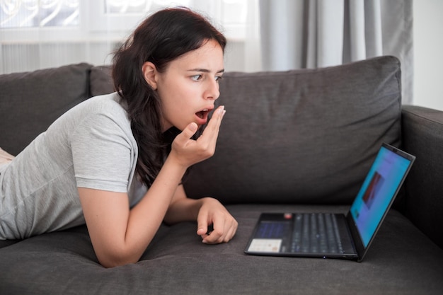 Photo young teen girl chatting with friends online on laptop lying on sofa