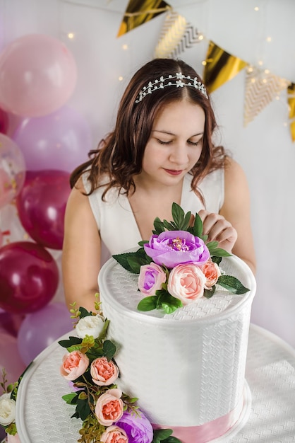 Young teen girl on her birthday with a big cake and balloons