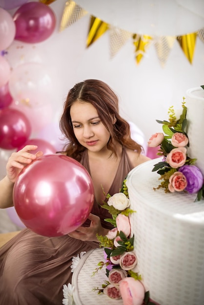 Foto giovane ragazza adolescente per il suo compleanno con una grande torta e palloncini