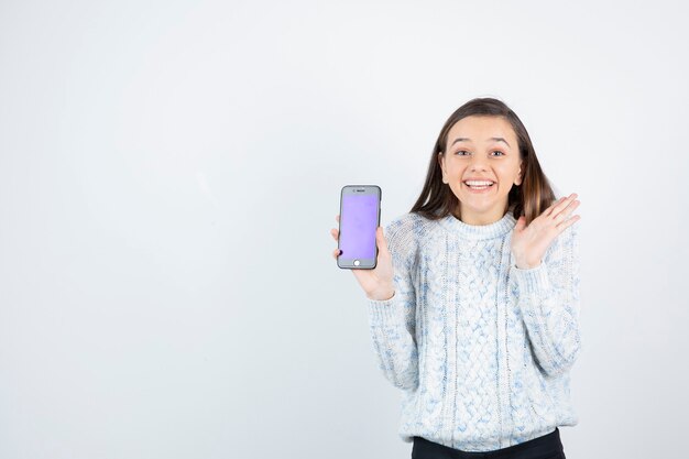 Young teen girl holding smartphone on white background.