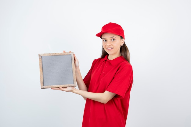 young teen girl in red uniform standing and holding frame