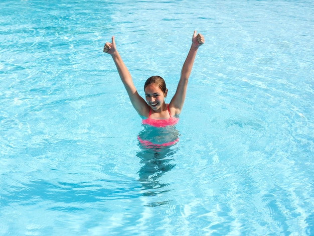 Young teen girl swims and have fun in the outdoor pool