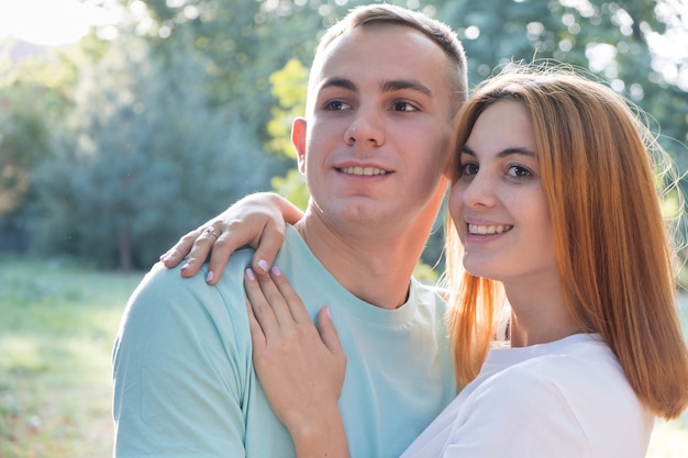 Young teenage couple outdoors. Pretty girl with red hair and handsome boy hugging together.