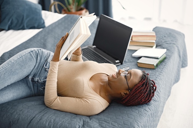 Young teenage girl lying on her bed studying in light bedroom at home