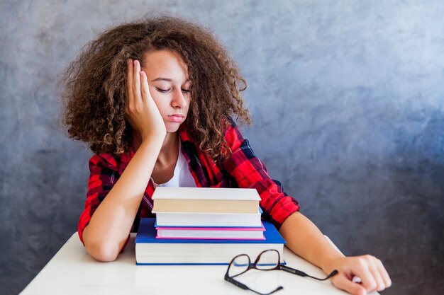 Foto giovane ragazza adolescente con i capelli ricci che riposa dall'apprendimento