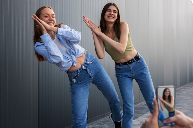 Young teenage girls recording reels of themselves outdoors for social media