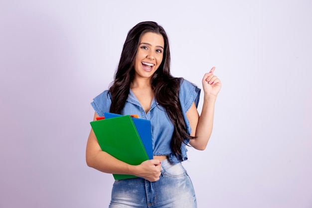 Young teenage student in denim clothing holds books points to free space for text