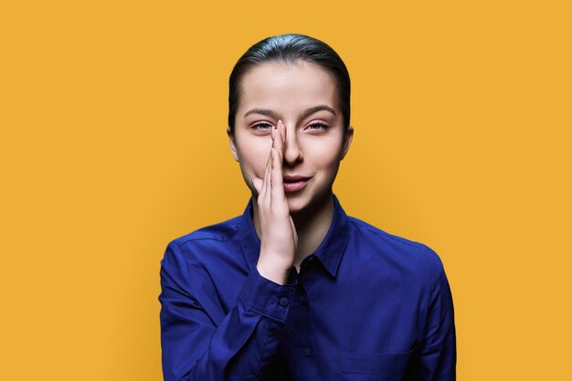 Photo young teenage woman whispering secret over yellow background