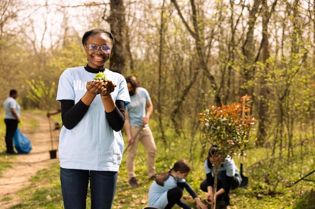 Foto giovane attivista adolescente che pianta piccole piantine verdi nel bosco