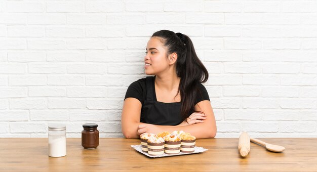 Young teenager Asian girl with lots of muffin cake looking to the side