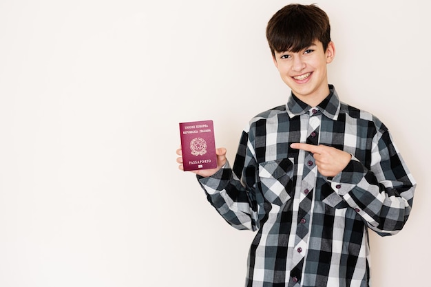 Young teenager boy holding Italy passport looking positive and happy standing and smiling with a confident smile against white background