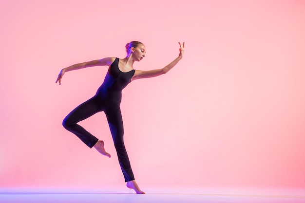 Фото Молодой танцор-подросток танцует на красном фоне студии. балет, танец, искусство, современность, концепция хореографии
