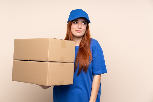 Young teenager delivery woman standing and looking to the side