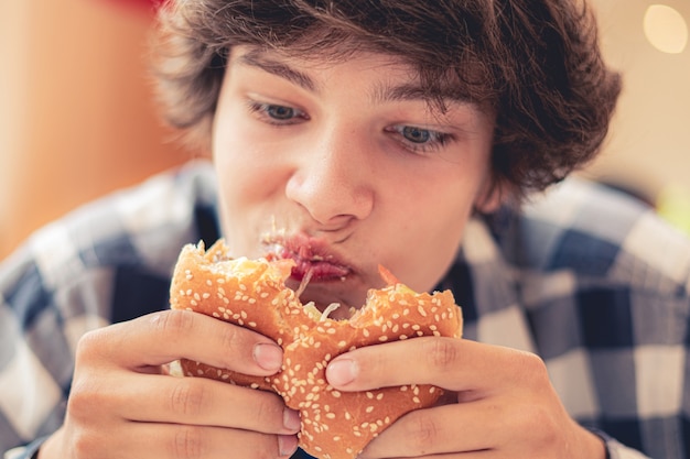 Young teenager eating hamburger