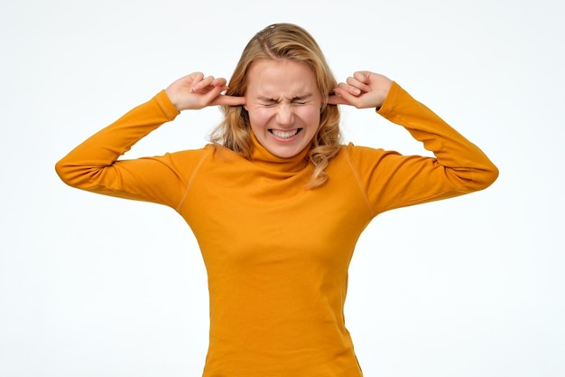 Photo young teenager female making wry face plugging ears with fingers