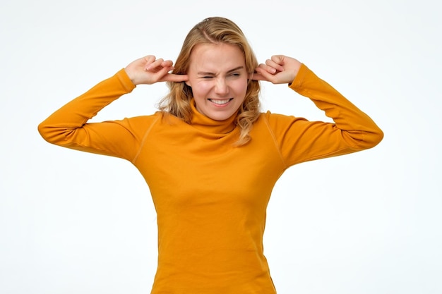 Foto femmina giovane adolescente che fa la faccia ironica tappando le orecchie con le dita