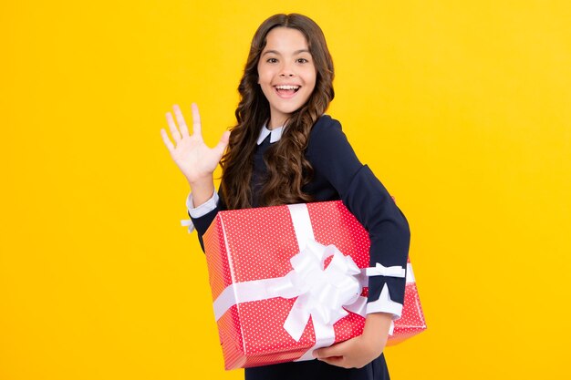 Young teenager girl child holding gift box isolated on yellow background gift for kids birthday