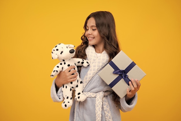 Young teenager girl child holding gift box isolated on yellow background gift for kids birthday