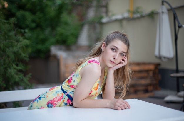 A young teenager girl in a dress sitting outdoor