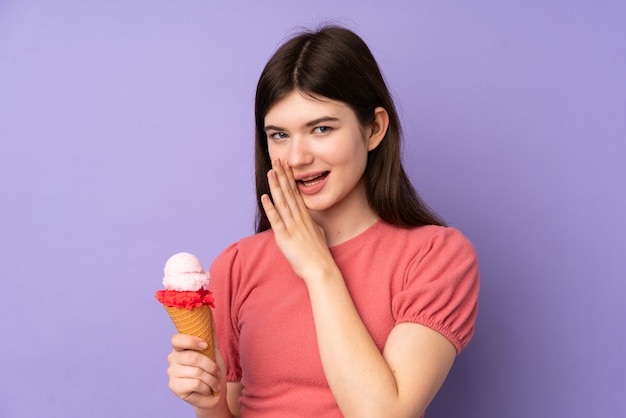 Young teenager girl holding a cornet ice cream over purple wall whispering something