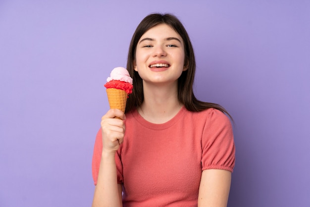 Young  teenager girl holding a cornet ice cream over purple wall