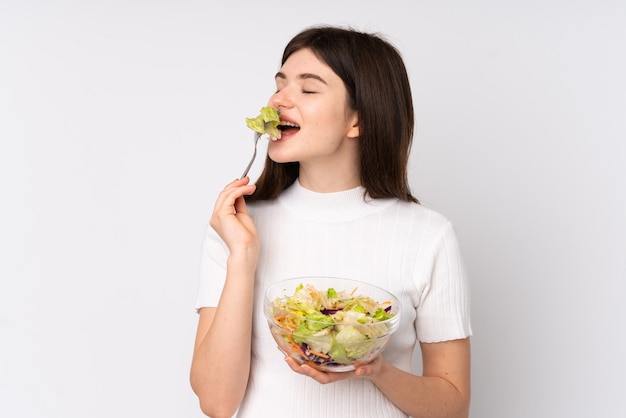 Young  teenager girl holding a salad over white wall