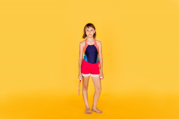 Young teenager girl jumping and playing badminton on yellow wall