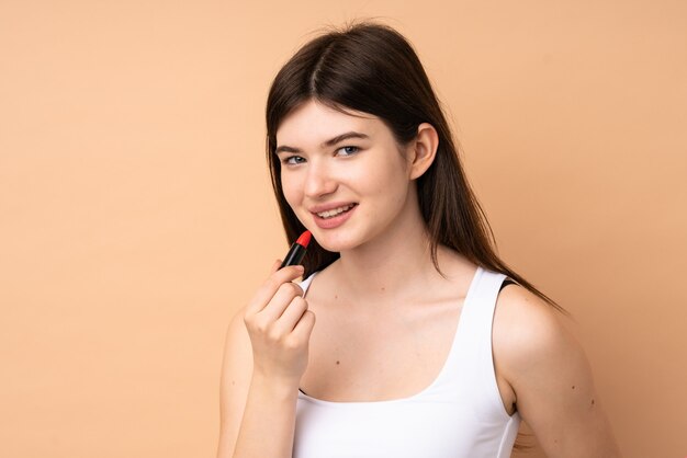 Young  teenager girl over wall holding red lipstick