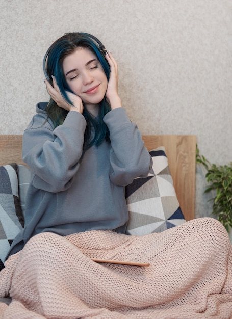 Young teenager girl with blue hair and headphones