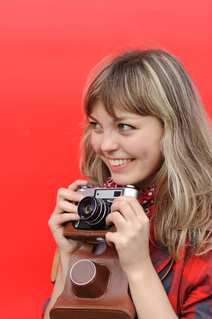 Foto giovane ragazza dell'adolescente con la vecchia cinepresa su sfondo rosso