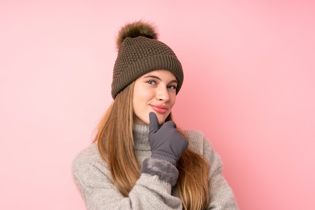 Photo young teenager girl with winter hat over isolated pink laughing