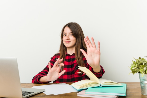 Photo young teenager going back to her routine doing homework rejecting someone.