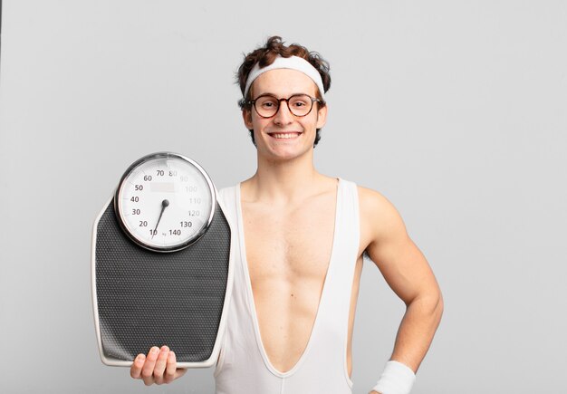 Young teenager man young crazy athlete happy expression and holding a scale