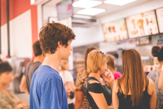 Young teenager standing in a queue to receive the fastfood