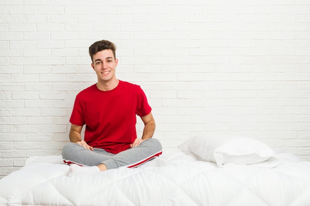 幸せ、笑顔、陽気なベッドの上の若い10代学生男。