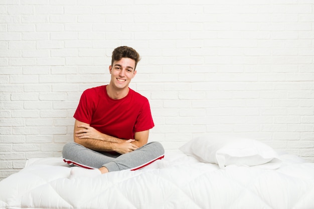 Young teenager student man on the bed laughing and having fun.