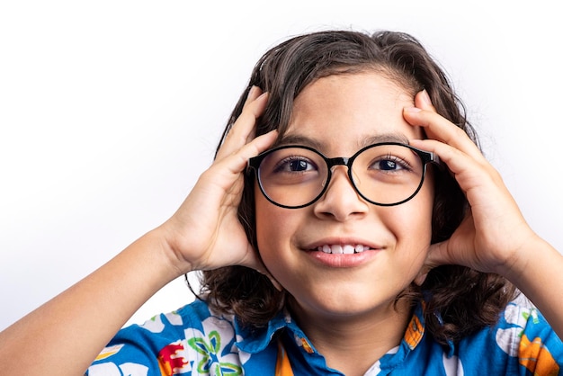 Young teenager with glasses caught in white background with hands on his head